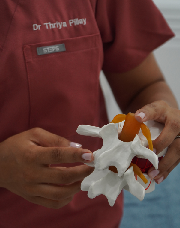 Dr Thriya Pillay demonstrating spinal alignment with a model at Bump & Beyond Clinic in Wimbledon.